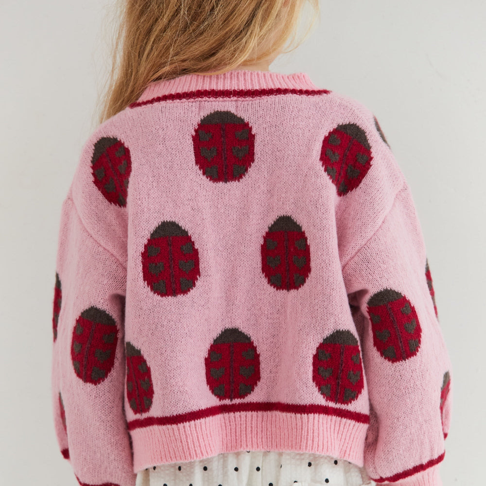 Rose lovebug cardigan van eht merk Juni aan bij meisje achterkant witte achtergrond