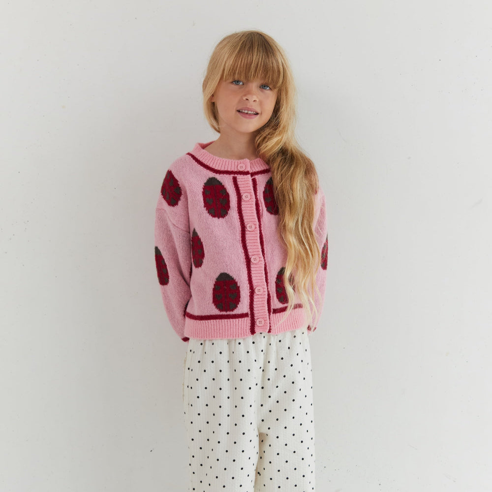 Rose lovebug cardigan van eht merk Juni aan bij meisje witte achtergrond